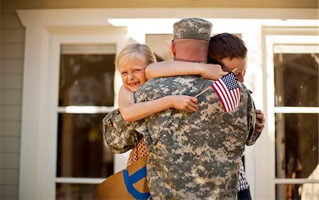 simsearch:6128-08781051,k - Army soldier hugging his two young children on the steps of their home. Foto de stock - Royalty Free Premium, Número: 6128-08737832