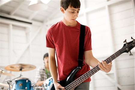 simsearch:6111-06837386,k - Teenage boy playing a bass guitar enthusiastically. Foto de stock - Royalty Free Premium, Número: 6128-08737933