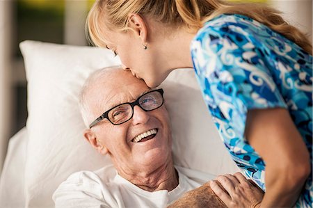 simsearch:6128-08738204,k - Friendly young rest home nurse cheers up her elderly male patient with a kiss on his forehead. Stock Photo - Premium Royalty-Free, Code: 6128-08738070