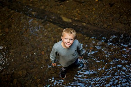 simsearch:649-03291839,k - Portrait of young boy looking up while standing  in the shallows of a river. Photographie de stock - Premium Libres de Droits, Code: 6128-08738001