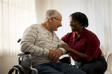 simsearch:640-03263216,k - Smiling female nurse comforting an elderly male patient in a wheelchair. Stock Photo - Premium Royalty-Free, Code: 6128-08738198