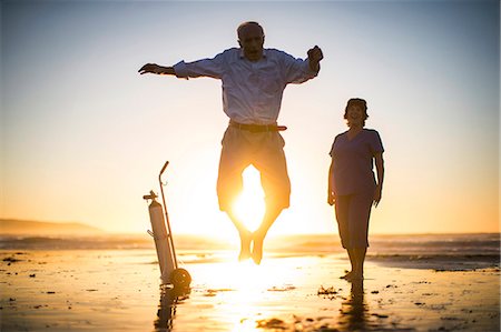 simsearch:6128-08738204,k - Portrait of a senior man jumping for joy on a beach while a laughing nurse looks on. Stock Photo - Premium Royalty-Free, Code: 6128-08738137