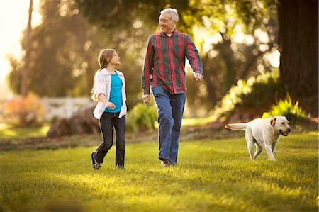 smiling senior people talking family - Smiling senior man bonding with his young granddaughter and golden labrador. Stock Photo - Premium Royalty-Free, Code: 6128-08738240