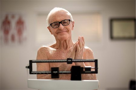 simsearch:6128-08738322,k - Senior man weighing himself on scales in a doctor's office. Photographie de stock - Premium Libres de Droits, Code: 6128-08738296