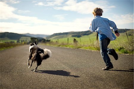 simsearch:614-08329432,k - Excited boy and his dog running down a rural country road. Stockbilder - Premium RF Lizenzfrei, Bildnummer: 6128-08738224