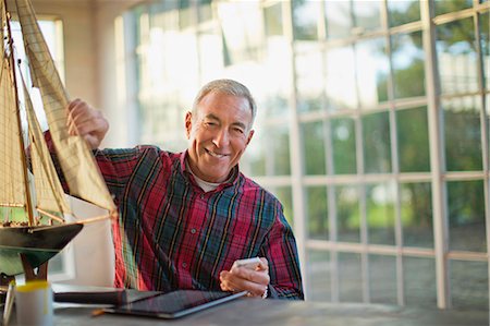 portrait guy in his garage - Portrait of a smiling senior man with a model boat inside his garage. Stock Photo - Premium Royalty-Free, Code: 6128-08738232