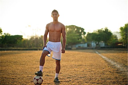 simsearch:6128-08766894,k - Portrait of a young soccer player standing with his foot on a ball while on a playing field. Foto de stock - Sin royalties Premium, Código: 6128-08738349