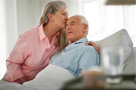 picture of old white woman on a sick bed - Senior man being kissed on the forehead by his wife as he lies in bed. Stock Photo - Premium Royalty-Free, Code: 6128-08738386