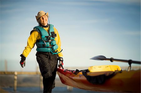 Smiling senior woman carrying the end of a kayak in the sunshine. Photographie de stock - Premium Libres de Droits, Code: 6128-08738308