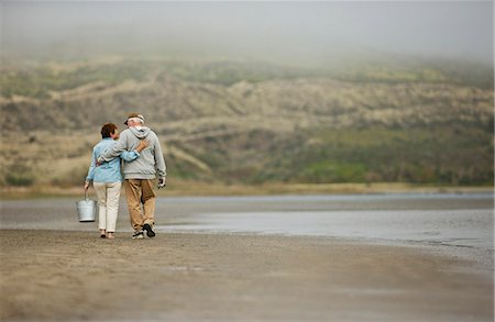 simsearch:649-06164557,k - Happy senior couple walking together on a beach. Fotografie stock - Premium Royalty-Free, Codice: 6128-08738324