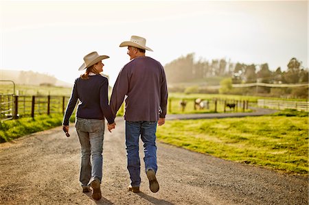 simsearch:614-03784139,k - Happy husband and wife farmers walking hand in hand along a rural country road near their farm. Stock Photo - Premium Royalty-Free, Code: 6128-08738334