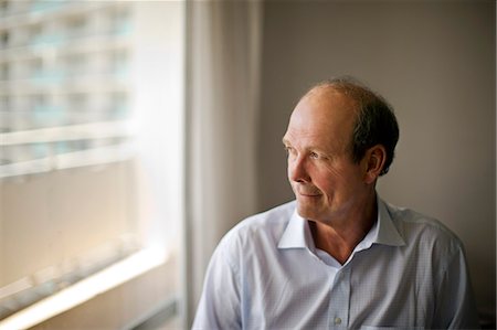 simsearch:693-06018584,k - Content mature man looking out the window of his living room. Photographie de stock - Premium Libres de Droits, Code: 6128-08738464