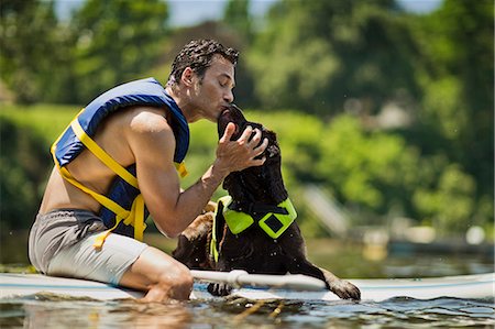 paddle boarder (all meanings) - Happy middle aged man kissing his dog. Stock Photo - Premium Royalty-Free, Code: 6128-08738477