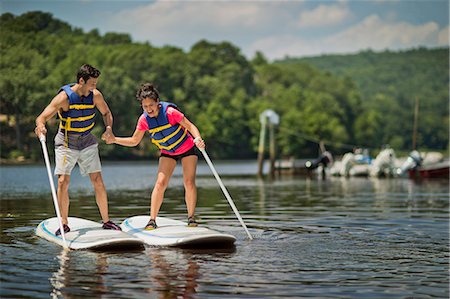 paddling on surf board - Young couple playfully flirting on paddleboards. Stock Photo - Premium Royalty-Free, Code: 6128-08738494