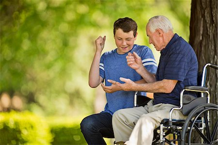 family and old - Smiling teenage boy playing rock paper scissors with his grandfather. Stock Photo - Premium Royalty-Free, Code: 6128-08738403