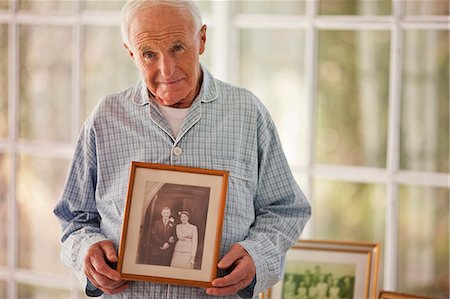Portrait of a senior man holding a family photo in a picture frame. Stock Photo - Premium Royalty-Free, Code: 6128-08738401