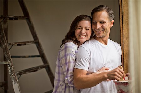 Smiling young wife embraces her handsome husband while they renovate their home and dream about the future. Stock Photo - Premium Royalty-Free, Code: 6128-08738582
