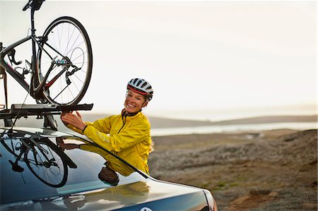 simsearch:6128-08738600,k - Smiling young woman attaching her bicycle to the roof of her car. Stock Photo - Premium Royalty-Free, Code: 6128-08738597