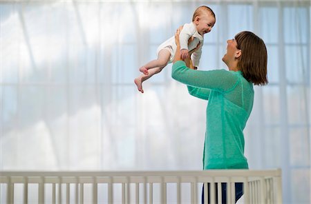 Cute baby boy laughing in delight as his young mother swings him up into the air. Stock Photo - Premium Royalty-Free, Code: 6128-08738643