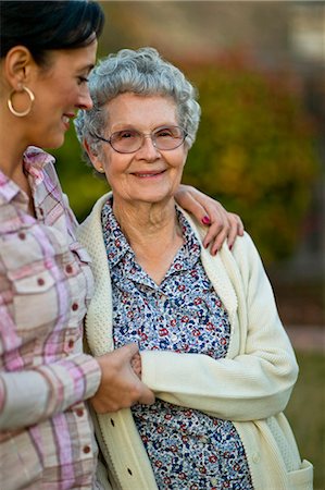 simsearch:6102-03904745,k - Middle-aged granddaughter smiling gently at her cheerful elderly grandmother as they walk in the garden together. Foto de stock - Sin royalties Premium, Código: 6128-08738611