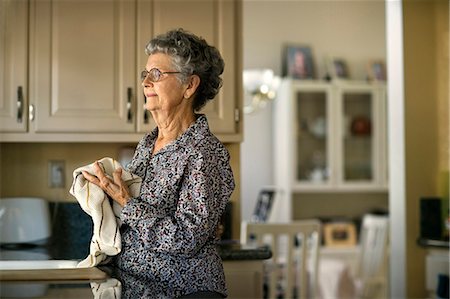 Elderly woman gazes thoughtfully out of the kitchen window while doing the dishes. Stock Photo - Premium Royalty-Free, Code: 6128-08738618