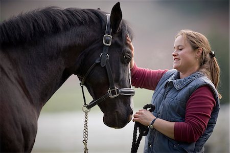 simsearch:6128-08840957,k - Young woman stroking her black horse on the nose. Stock Photo - Premium Royalty-Free, Code: 6128-08840950