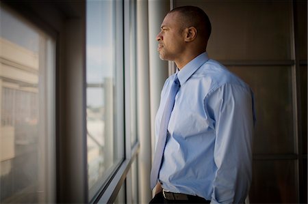 stay - Mid-adult businessman looking out a window of an office. Stock Photo - Premium Royalty-Free, Code: 6128-08840958