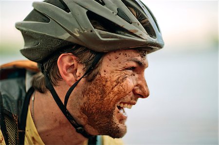 shoulder ride side view - Happy young mountain biker laughing as he is covered in mud. Stock Photo - Premium Royalty-Free, Code: 6128-08840990