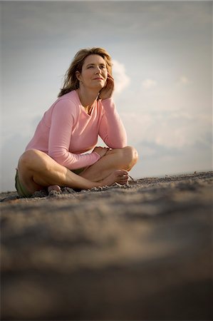 simsearch:614-08867718,k - Mid-adult woman sitting with crossed legs on a beach. Photographie de stock - Premium Libres de Droits, Code: 6128-08840907