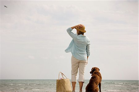 simsearch:6128-08840957,k - Woman standing on a beach with her dog. Fotografie stock - Premium Royalty-Free, Codice: 6128-08840917