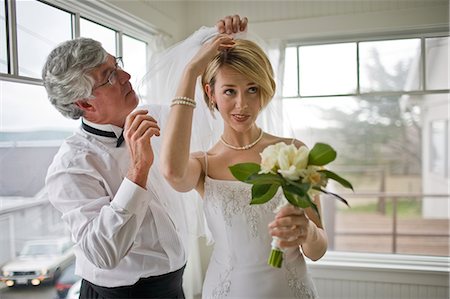 simsearch:693-08769608,k - Young bride getting help to attach her veil while holding her bouquet inside a room. Stock Photo - Premium Royalty-Free, Code: 6128-08825343