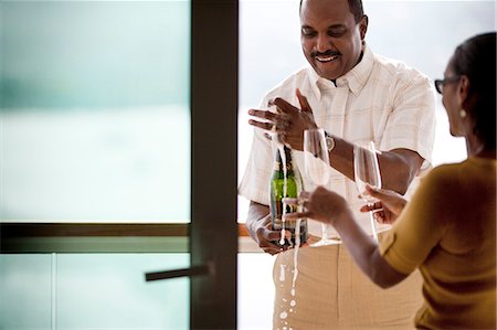 simsearch:614-06897980,k - Middle aged African American couple celebrating success and opening bottle of champagne on house deck. Stockbilder - Premium RF Lizenzfrei, Bildnummer: 6128-08825370