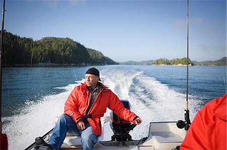 swiftly - Mature man steering a motor at the rear of a boat. Stock Photo - Premium Royalty-Free, Code: 6128-08825378