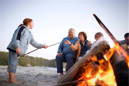 simsearch:832-03640492,k - Family sitting around a campfire toasting marshmallows Fotografie stock - Premium Royalty-Free, Codice: 6128-08825387