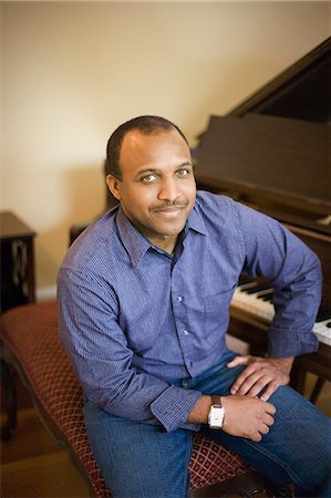 Portrait of a smiling mid-adult man seated at a piano. Stock Photo - Premium Royalty-Free, Code: 6128-08825394