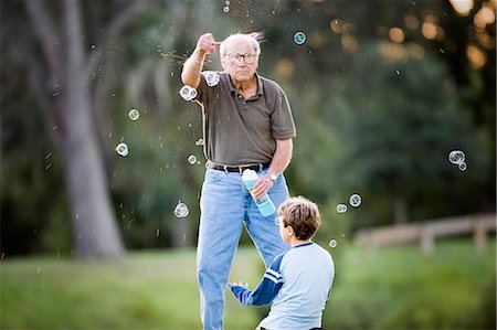 simsearch:400-04065514,k - Senior adult man making bubbles for his young grandson outside at sunset. Foto de stock - Sin royalties Premium, Código: 6128-08825423