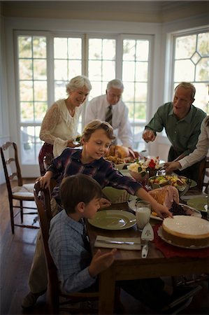 Happy family gathered around a dining table on Christmas day. Foto de stock - Sin royalties Premium, Código: 6128-08825433