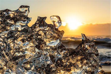 Jokulsarlon glacier lagoon, Iceland. Sunlight reflections over a small black of ice on the shore. Photographie de stock - Premium Libres de Droits, Code: 6129-09044025