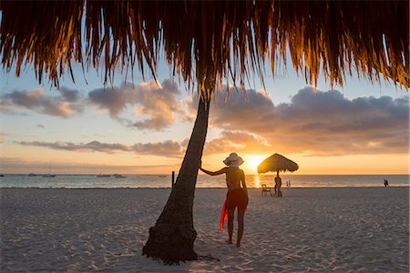 Bavaro Beach, Bavaro, Higuey, Punta Cana, Dominican Republic. Woman by thatch umbrellas on the beach at sunrise (MR). Stockbilder - Premium RF Lizenzfrei, Bildnummer: 6129-09044557