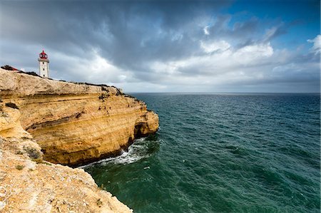 promontorio - Clouds frame the lighthouse on cliffs overlooking the Atlantic Ocean Carvoeiro Lagoa Municipality Algarve Portugal Europe Foto de stock - Sin royalties Premium, Código: 6129-09044887