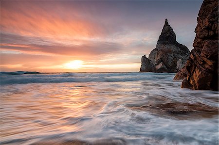 The fiery sky at sunset is reflected on the ocean waves and cliffs Praia da Ursa Cabo da Roca Colares Sintra Portugal Europe Foto de stock - Sin royalties Premium, Código: 6129-09044827