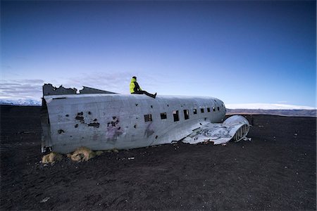 escombros - Man on the top of the abandoned US Navy DC plane on the beach of Solheimasandur, Sudurland, Iceland, Europe Foto de stock - Sin royalties Premium, Código: 6129-09057700