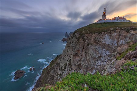 faro - Sunrise on the cape and lighthouse of Cabo da Roca overlooking the Atlantic Ocean Sintra Portugal Europe Foto de stock - Sin royalties Premium, Código: 6129-09058174