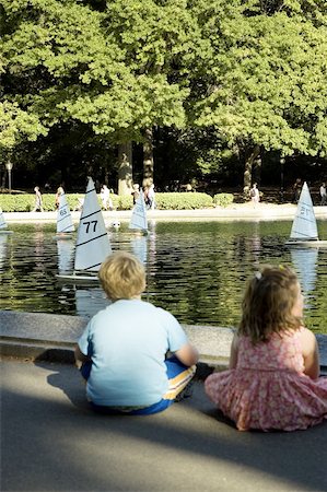 Rear view of a boy and a girl sitting beside a lake, New York City, New York State, USA Foto de stock - Sin royalties Premium, Código: 625-00805042