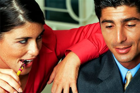 Businessman and businesswoman with arm on man's shoulder and biting pen, close-up Stock Photo - Premium Royalty-Free, Code: 625-00802293