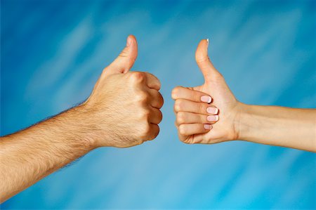 Close-up of a man and a woman's hands making a thumbs up sign Stock Photo - Premium Royalty-Free, Code: 625-00802497