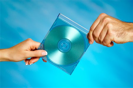 Close-up of a man and a woman's hands holding a compact disk Stock Photo - Premium Royalty-Free, Code: 625-00802499