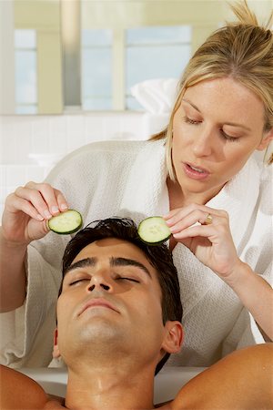 Close-up of a young woman putting cucumber slices on a young man's eye Stock Photo - Premium Royalty-Free, Code: 625-00837607