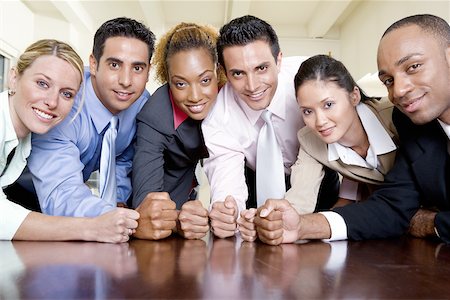 Portrait of a group of business executives with their fists on a table Stock Photo - Premium Royalty-Free, Code: 625-00837844