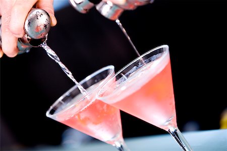 pouring cocktail shaker into glass - Close-up of a person's hand pouring martini into martini glasses Stock Photo - Premium Royalty-Free, Code: 625-00837956